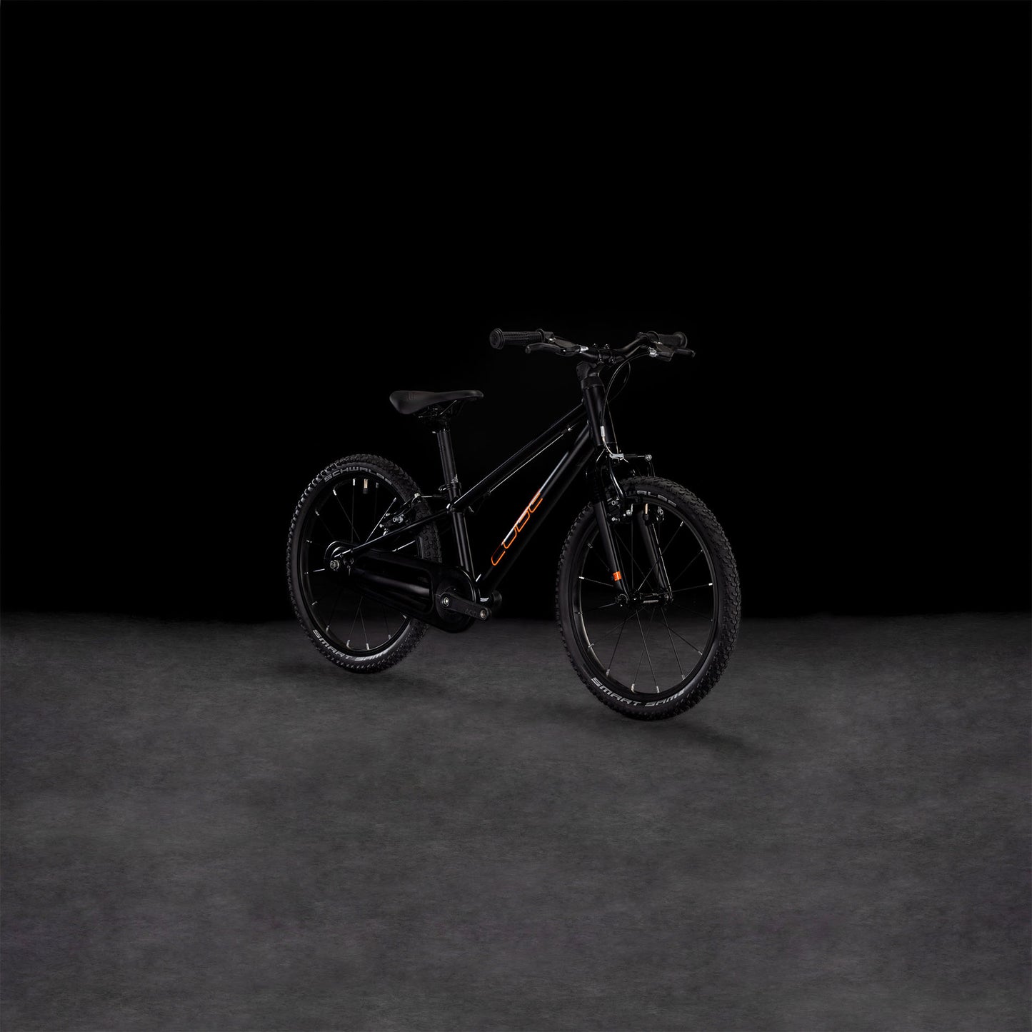 Das CUBE Numove 180 black'n'orange 2025, ein Kinder-Geländefahrrad aus robustem 6061er-Aluminium, zeigt sich im Seitenprofil vor einem dunklen Hintergrund. Der schwarze Rahmen ist mit auffälligen orangefarbenen Akzenten versehen.
