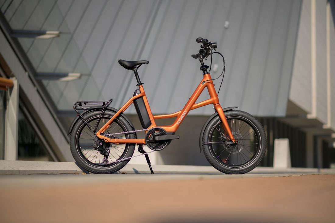 Oranges CUBE Kompakt-E-Bike mit kleinen Laufrädern vor einem Gebäude geparkt