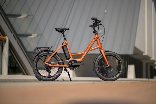 Oranges CUBE Kompakt-E-Bike mit kleinen Laufrädern vor einem Gebäude geparkt