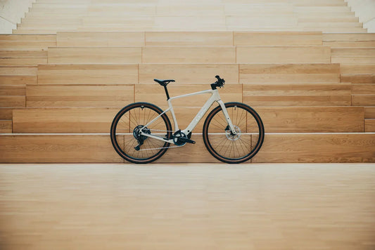 Weißes CUBE Nuroad Hybrid Gravel-E-Bike mit Dropbar-Lenker vor einer Holzwand