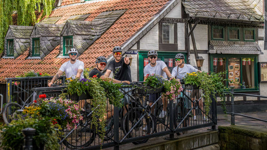 Gruppe von Radfahrern mit CUBE Bikes auf einer Brücke vor Fachwerkhäusern