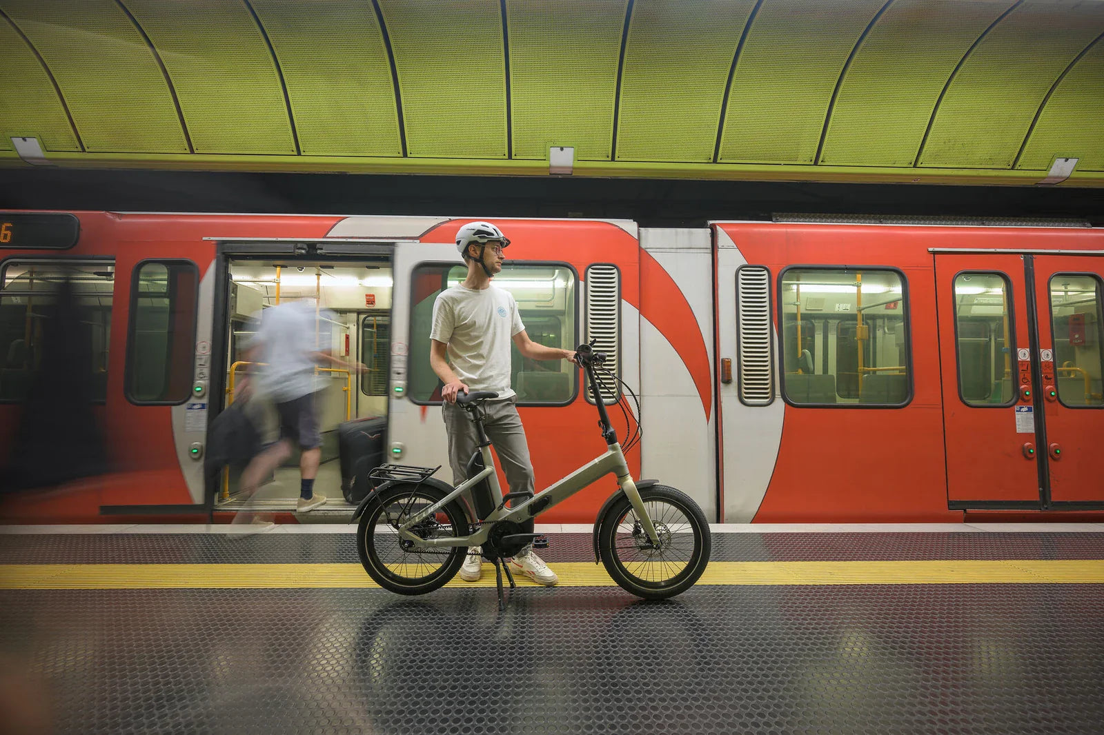 CUBE Fold Hybrid Falt E-Bike – Mann mit Faltrad am U-Bahn-Bahnsteig vor fahrendem Zug