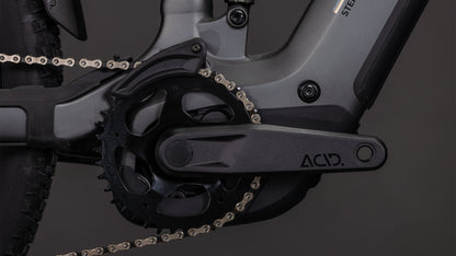 Nahaufnahme der Cube Stereo Hybrid ONE22 Race 800 slabgrey'n'chrome 2026 Kurbelgarnitur und Kettenblatt, mit einem ACID-gekennzeichneten Kurbelarm und Shimano 12-fach XT Schaltung von CUBE vor dunklem Hintergrund.