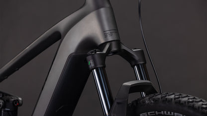 Nahaufnahme des mattschwarzen CUBE Stereo Hybrid ONE22 Race 800 slabgrey'n'chrome 2026-Rahmens und der Federgabel, mit Noppenreifen und Schwalbe-Branding sowie Shimano 12-fach XT-Schaltungsdetails vor dunklem Hintergrund.