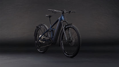 Das CUBE Stereo Hybrid ONE22 SLX 800 FE indigoblue'n'blue 2026 E-Mountainbike mit Bosch CX Motor, breiten Reifen, Schutzblech und Scheibenbremsen ist auf einem dunklen Hintergrund mit Farbverlauf leicht nach links ausgerichtet.