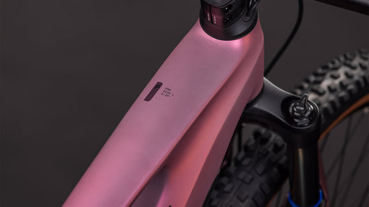 Nahaufnahme des CUBE Stereo Hybrid ONE44 Pro 800 shiftblush'n'raisin 2026 Rahmens, die das Oberrohr, die Federgabel und ein kleines Display zeigt. Ausgestattet mit Bosch CX-Motor; der Hintergrund ist dunkel und unscharf.