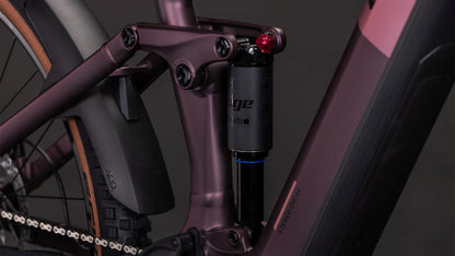 Nahaufnahme eines CUBE Stereo Hybrid ONE44 Pro 800 shiftblush'n'raisin 2026 mit schwarzem Stoßdämpfer am mattlila Rahmen mit Bosch CX Motor sowie Hinterrad, Kette und Schutzblech.