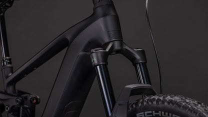 Nahaufnahme der vorderen Federgabel des CUBE Stereo Hybrid ONE44 EX 800 blackline 2026, des robusten Reifens mit sichtbarem Branding und eines Teils des klobigen Rahmens, alles vor einem dunklen Hintergrund, der das Fully-MTB-Design betont.