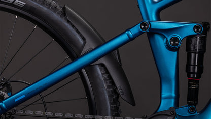 Nahaufnahme des CUBE Stereo Hybrid ONE44 EX 800 electricblue'n'blue 2026 E-MTB-Rahmens mit Hinterradfederung, schwarzem Schutzblech, Reifen und einem Teil des Bosch CX Antriebssystems vor einem dunklen Hintergrund.