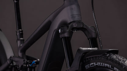 Nahaufnahme eines matten, irongrünen und verchromten CUBE Stereo Hybrid ONE44 EXC 800 FE Mountain E-Bikes, das die vordere Federgabel, den Rahmen, die Schwalbe-Reifen und den Bosch CX-Motor vor einem dunklen Hintergrund zeigt.