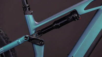Nahaufnahme des CUBE Stereo Hybrid ONE44 HPC Race 800 smaragdgrey'n'prism (2026) Rahmens mit Hervorhebung des hinteren Dämpfers und des Gestänges. Das mattblaue Gradienten-Finish sorgt für einen eleganten, hochwertigen Look vor einem dunklen Hintergrund.