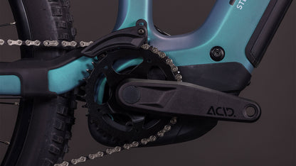 Nahaufnahme der CUBE Stereo Hybrid ONE44 HPC Race 800 smaragdgrey'n'prism 2026 Kurbelgarnitur mit schwarzem Kettenblatt, ACID-Pedalarm und silberner Kette, die leistungsstarke Carbon-Antriebskomponenten präsentiert.