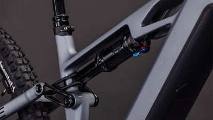 Nahaufnahme des CUBE Stereo Hybrid ONE44 HPC SLX Evo 800 (slategrey'n'black, 2026) Rahmens, die das hintere Federungssystem mit schwarzem Stoßdämpfer, detaillierter Anlenkung und leistungsstarkem Bosch CX Motor vor dunklem Hintergrund zeigt.