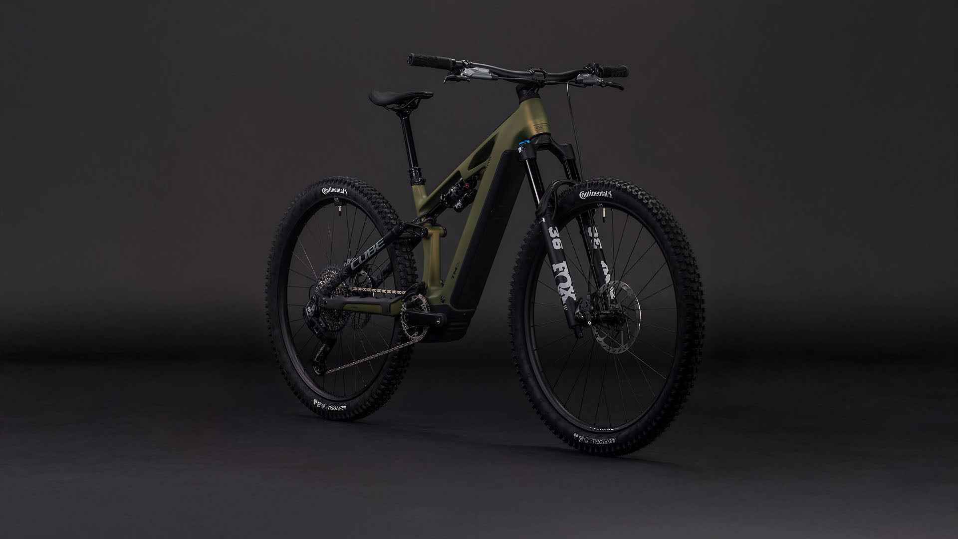 Das CUBE Stereo Hybrid ONE44 HPC TM 800 reedgreen'n'matrix 2026 E-MTB verfügt über breite Stollenreifen, einen schwarzen Lenker, Stoßdämpfer vorne und hinten und einen Bosch CX-Motor, der vor einem dunklen, nahtlosen Hintergrund steht.