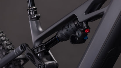 Nahaufnahme der Hinterradaufhängung des CUBE Stereo Hybrid ONE77 HPC Race 800. Hervorzuheben sind der Stoßdämpfer und das irongrey'n'black Rahmenfinish vor einem dunklen Hintergrund.