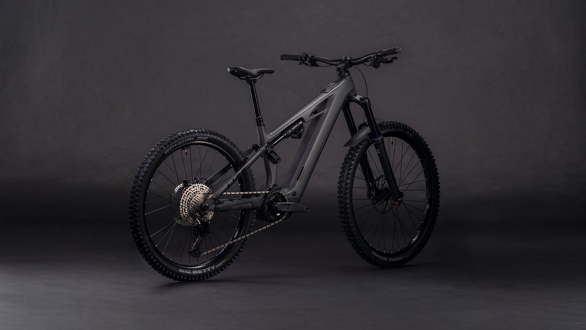 Das CUBE Stereo Hybrid ONE77 HPC Race 800 irongrey'n'black 2026 Elektro-Mountainbike ist vor einem dunklen Hintergrund abgebildet, der die dicken Reifen, den Bosch CX-Motor, den Shimano XT 12-Gang-Antrieb und die Anordnung des Akkus hervorhebt.