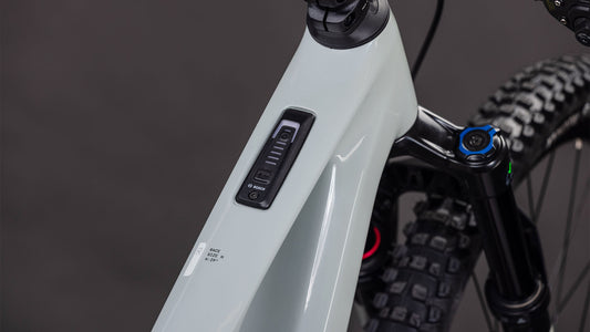 Nahaufnahme des CUBE AMS Hybrid ONE44 C:62 Race 400X reedbeige'n'black 2026 Rahmens von CUBE, die das Bosch-Bedienfeld und die Batterieanzeige auf dem Oberrohr mit einem Bosch SX Motor zeigt. Die vordere Federgabel und der Reifen sind im Hintergrund zu sehen.