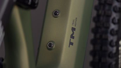 Nahaufnahme eines CUBE AMS Hybrid 177 C:62 TM 600X reedgreen'n'matrix 2026 Rahmens mit "Trail Motion" Aufdruck, zwei Befestigungsschrauben, einem sichtbaren Fahrradreifen und angetrieben von einem Bosch CX Motor für höchste E-Mountainbike Performance.