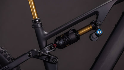 Nahaufnahme der Hinterradaufhängung des CUBE AMS Hybrid 177 C:62 AT 600X carbon'n'gold 2026, wobei der gold-schwarze Stoßdämpfer auf einem mattschwarzen Carbonrahmen mit sichtbaren Anlenkungselementen ins Auge fällt.