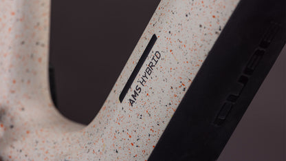 Nahaufnahme eines Cube AMS Hybrid 177 C:62 SUPER TM 600X Rahmens in schilfbeigegrit'n'orange, mit "CUBE" Branding und ausgestattet mit einem Bosch CX-R Motor für optimale Leistung.