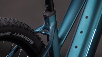 Nahaufnahme des CUBE Reaction Hybrid ONE 800 in royalgreen'n'prism Trapeze 2026, die das Sitzrohr, den Hinterreifen mit SMART SAM-Branding, einen Teil des Unterrohrs und ein leistungsstarkes Bosch-Motorsystem vor einem unscharfen Hintergrund zeigt.