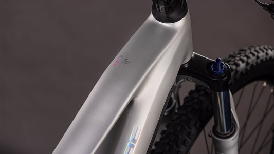 Nahaufnahme des matt-silbernen Rahmens und der Federgabel des CUBE Reaction Hybrid ONE 800 sleekgrey'n'prism 2026, die das glatte, kantige Design, den integrierten Bosch-Motor und die Stollenreifen zeigt.
