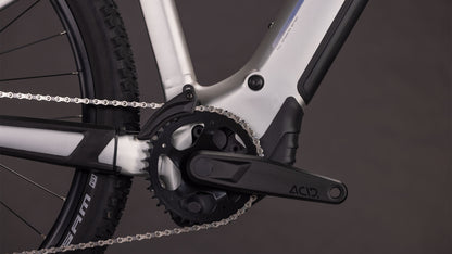 Nahaufnahme eines CUBE Reaction Hybrid ONE 800 sleekgrey'n'prism 2026 Kurbelsatz, Kette und Rahmen mit ACID-gekennzeichnetem Pedalarm und sichtbarem Bosch-Motor. Der dunkle Hintergrund betont die herausragenden Komponenten dieses E-Bikes.