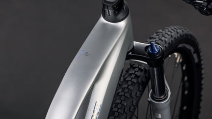 Nahaufnahme des CUBE Reaction Hybrid ONE 800 sleekgrey'n'prism Trapeze 2026 Rahmens, die das Oberrohr, den Bosch Motor, die Federgabel und den Vorderreifen vor einem dunklen Hintergrund zeigt.
