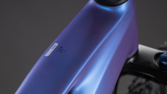 Nahaufnahme des metallisch blauen CUBE Reaction Hybrid ONE 800 (blueiris'n'reflect, GRÖSSE: L und M 22.2), mit Shimano Cues Schaltung, vor einem unscharfen dunklen Hintergrund - perfekt ausgestattet für jede Fahrt.
