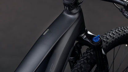 Nahaufnahme des CUBE Reaction Hybrid Pro 800 blackline 2026 E-Mountainbike-Rahmens mit mattschwarzem Finish, auffälliger Bosch CX Antrieb-Integration, sichtbarer Vorderradfederung, detailliertem Reifenprofil und blauem Einstellknopf in der Nähe des Lenkers.
