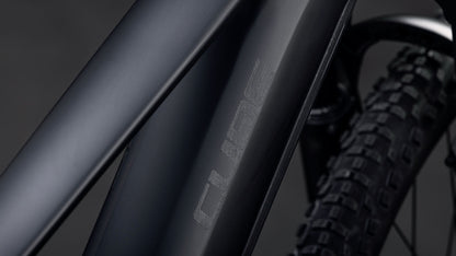 Nahaufnahme des Cube Reaction Hybrid Pro 800 blackline 2026 Rahmens in mattschwarz von CUBE, mit sichtbarem strukturierten Reifen und angedeutetem leistungsstarken Bosch CX Antrieb plus 800 Wh Akku im Hintergrund.