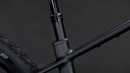 Nahaufnahme des CUBE Reaction Hybrid Pro 800 blackline 2026 Rahmens mit der mattschwarzen Sattelstütze, dem Hinterrad und dem Oberrohr. Vor dem dunklen Hintergrund ist ein Bosch CX Motor zu sehen.