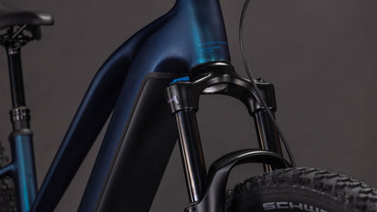 Nahaufnahme des Cube Reaction Hybrid Pro 800 nebular'n'dazzle Trapeze 2026 von CUBE, die den mattblauen Rahmen, den Bosch CX-Antrieb, die schwarzen Komponenten und das Schwalbe-Reifenbranding vor einem dunklen Hintergrund zeigt.