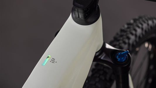 Nahaufnahme des CUBE Reaction Hybrid Pro 800 desertstone'n'driedherbs 2026 Rahmens mit einem kleinen beleuchteten Digitaldisplay, einem Teil des Lenkers, der Federgabel mit Bosch CX-Antrieb und einem Noppenreifen im Hintergrund.