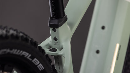Nahaufnahme eines CUBE Reaction Hybrid Pro 800 desertstone'n'driedherbs 2026 Rahmens, wobei die Sattelstütze, das Sitzrohr mit den Einstellmarkierungen und ein Teil eines schwarzen Schwalbe-Reifens hervorgehoben werden. Der sanft verschwommene Hintergrund hebt die Details hervor.