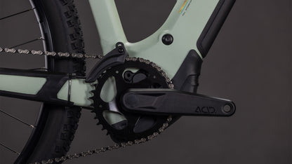 Nahaufnahme der CUBE Reaction Hybrid Pro 800 Kurbelgarnitur und des Kettenblatts, mit einem Teil des Hinterradreifens und der Kette auf einem hellgrünen und schwarzen Rahmen, mit Bosch CX-Antriebsdetails und ACID-Branding auf dem Kurbelarm.