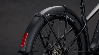 Nahaufnahme des Hinterrads des CUBE Reaction Hybrid Pro 800 FE blackline 2026 mit der Shimano XT Schaltung, dem schwarzen Schutzblech, dem roten Reflektor und dem Rahmen vor dunklem Hintergrund.