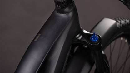 Nahaufnahme des CUBE Reaction Hybrid Pro 800 FE blackline Trapeze 2026, die den mattschwarzen Rahmen, das Oberrohr, den Steuersatz, den blauen Knopf der Vorderradaufhängung, die Shimano XT 12-Gang-Schaltung und einen Teil des Vorderrads zeigt.