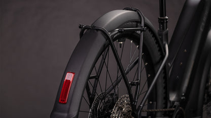 Nahaufnahme des Hinterrads eines CUBE Cube Reaction Hybrid Pro 800 FE blackline Trapeze 2026, mit Schutzblech mit rotem Reflektor, Rahmen, Shimano XT 12-fach Schaltung, Kette und Stützstreben vor dunklem Hintergrund.