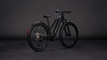 Das CUBE Reaction Hybrid Pro 800 FE blackline Trapeze 2026, ein mattschwarzes E-Bike mit dicken Reifen, Hinterradschutzblech und Scheibenbremsen, ausgestattet mit einem Bosch CX Motor, wird in einem Studio mit dunklem Hintergrund ausgestellt und von der Seite und von hinten gezeigt.