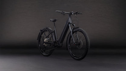 Das CUBE Reaction Hybrid Pro 800 FE blackline Easy Entry 2026, ein mattschwarzes E-Bike mit dicker Bereifung, Federgabel, Schutzblechen und Durchstiegsrahmen, besticht durch einen Bosch CX-Motor und modernes Design vor dunklem Hintergrund.