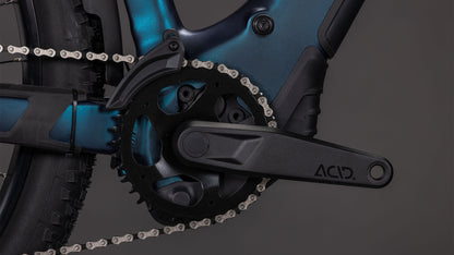 Nahaufnahme einer schwarzen Kurbelgarnitur, eines schwarzen Kettenblatts und einer schwarzen Kette am CUBE Reaction Hybrid Pro 800 FE nebular'n'dazzle 2026 E-Bike, mit dem ACID-Logo auf dem Kurbelarm und der Integration des Bosch CX-Motors vor einem dunkelgrauen Hintergrund.
