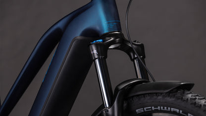 Nahaufnahme des CUBE Reaction Hybrid Pro 800 FE nebular'n'dazzle Trapeze 2026 mit dunkelblauem Rahmen, Federgabel, Schwalbe-Reifen, sichtbaren Brems- und Schaltzügen und Shimano XT-Schaltung für reibungslose Schaltvorgänge vor dunklem Hintergrund.