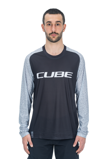 Ein Mann mit kurzen dunklen Haaren und einem Bart trägt das Cube VERTEX Rundhalstrikot langarm schwarz, mit weiß gemusterten Ärmeln, Kompatibilität des Halsbandes und einem auffälligen "CUBE"-Branding auf der Brust. Er steht mit dem Gesicht nach vorne vor einem weißen Hintergrund.