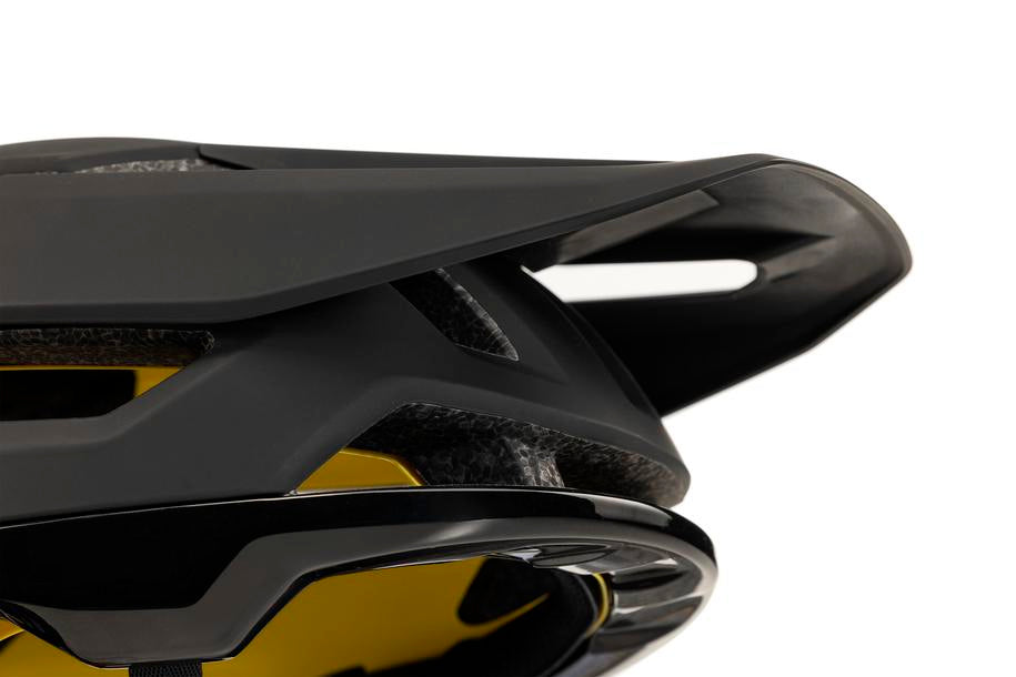 Nahaufnahme der Rückseite des Cube Helm TROOPER / MTB Enduro Helm in schwarz, die das aerodynamische Design, die kantigen Linien, die Belüftungsschlitze und die gelbe Innenpolsterung der MIPS Technologie zeigt.