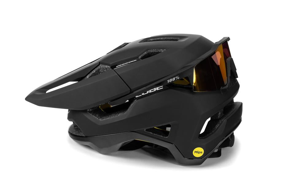Der mattschwarze Cube CUBE Helm TROOPER / MTB Enduro Helm verfügt über kantige Belüftungsöffnungen, eine an der Vorderseite angeklippte Sonnenbrille und einen sichtbaren gelben MIPS Technologie Aufkleber für erweiterte Sicherheit.