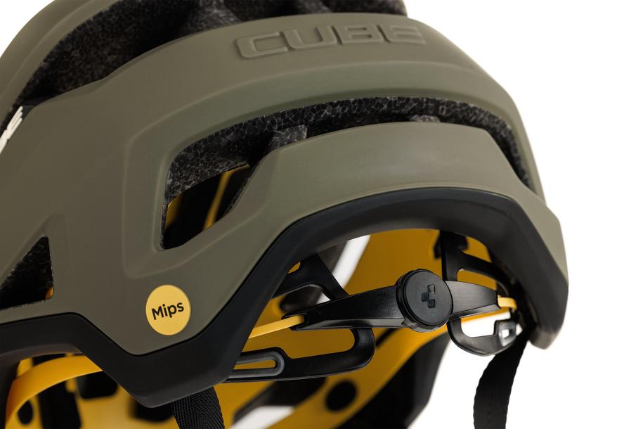 Nahaufnahme des grünen Cube Helms TROOPER von Cube mit MIPS-Technologie mit sichtbarem Sicherheitssystem-Label, einstellbarem Innenmechanismus und gut gestalteten Belüftungskanälen vor weißem Hintergrund.