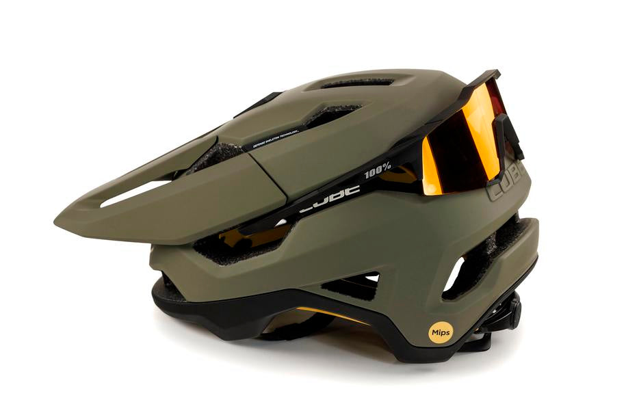Der CUBE Helm TROOPER von Cube verfügt über ein mattes olivgrünes Finish, eckige Belüftungskanäle, ein gelbes MIPS-Sicherheitslogo, ein schwarzes Visier und eine vorne montierte Sonnenbrille.