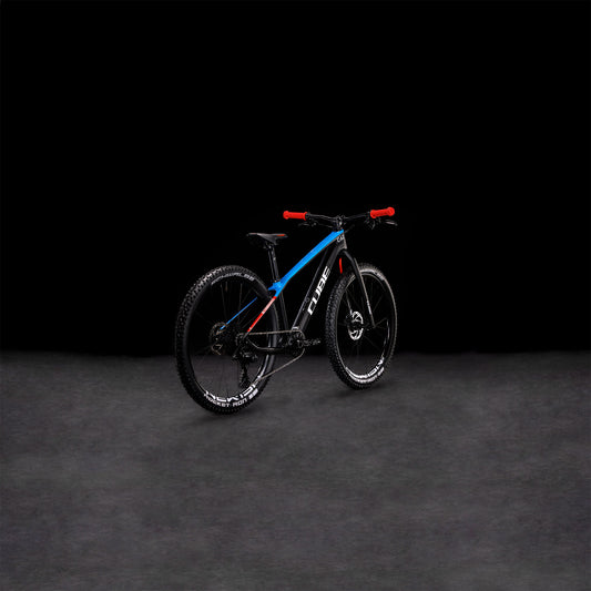 Das CUBE Elite 240 C:62 Pro carbon'n'blue'n'red 2024, ein CUBE Race-Mountainbike mit Vollcarbonrahmen in Blau und Schwarz, rotem Lenker und dicken Reifen, steht auf einer dunklen Fläche vor schwarzem Hintergrund.