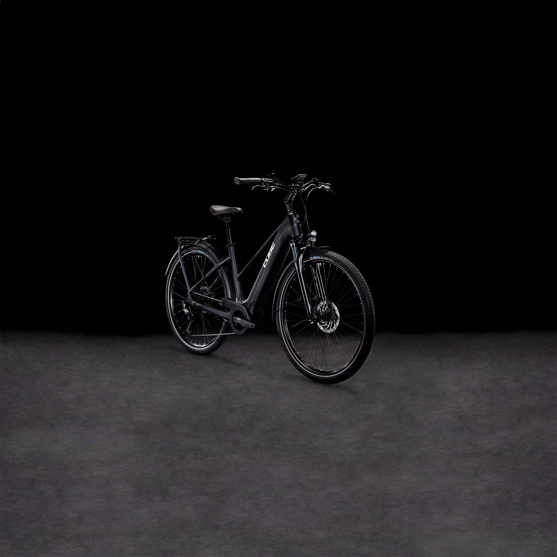 Das CUBE Touring Hybrid Pro 625 black'n'metal Trapeze 2024 Elektrofahrrad mit Vorderradaufhängung ist vor einem dunklen, nahtlosen Hintergrund abgebildet, der die elegante, matte Oberfläche und den integrierten Bosch Performance Motor betont.